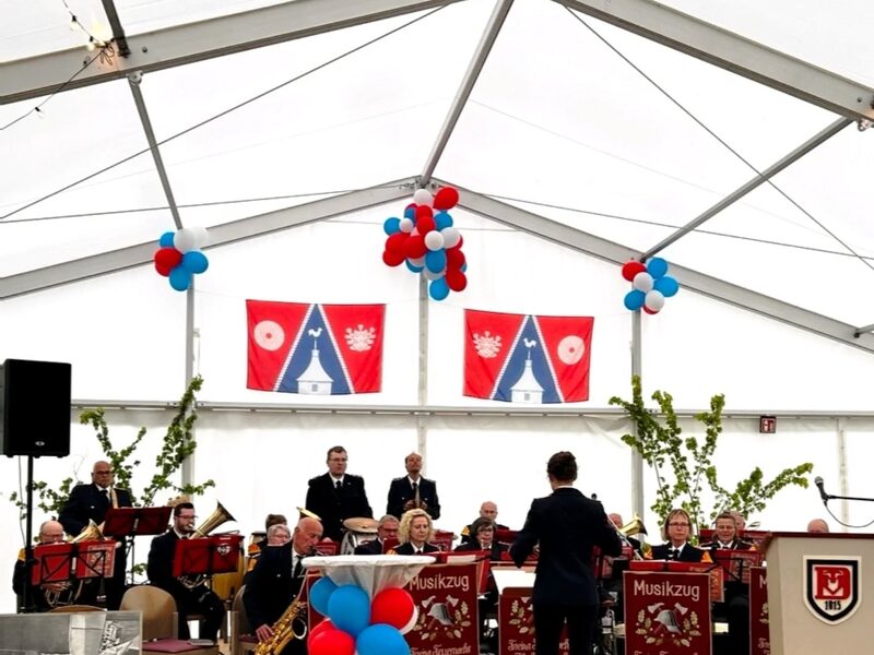 Der Musikzug spielt im geschmückten Festzelt, vorne der Dirigent.