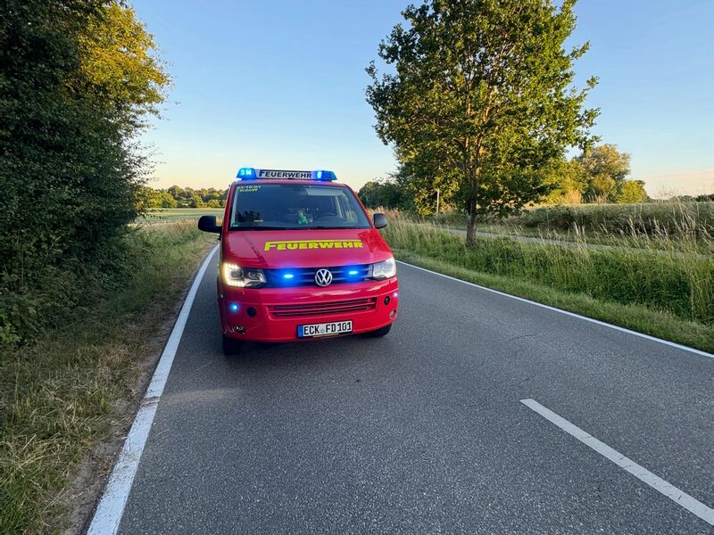 Feuerwehrfahrzeug mit Blaulicht auf einer Landstraße.
