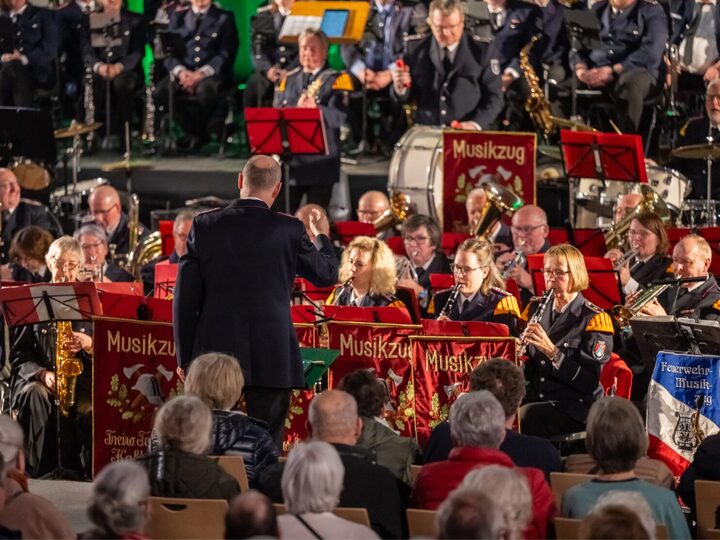 Blick über das Publikum auf die Bühne, wo der Musikzug mit Bläsern und Schlagzeug spielt.